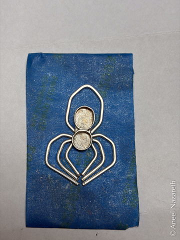 A piece of blue tape with a spider's body and legs taped down